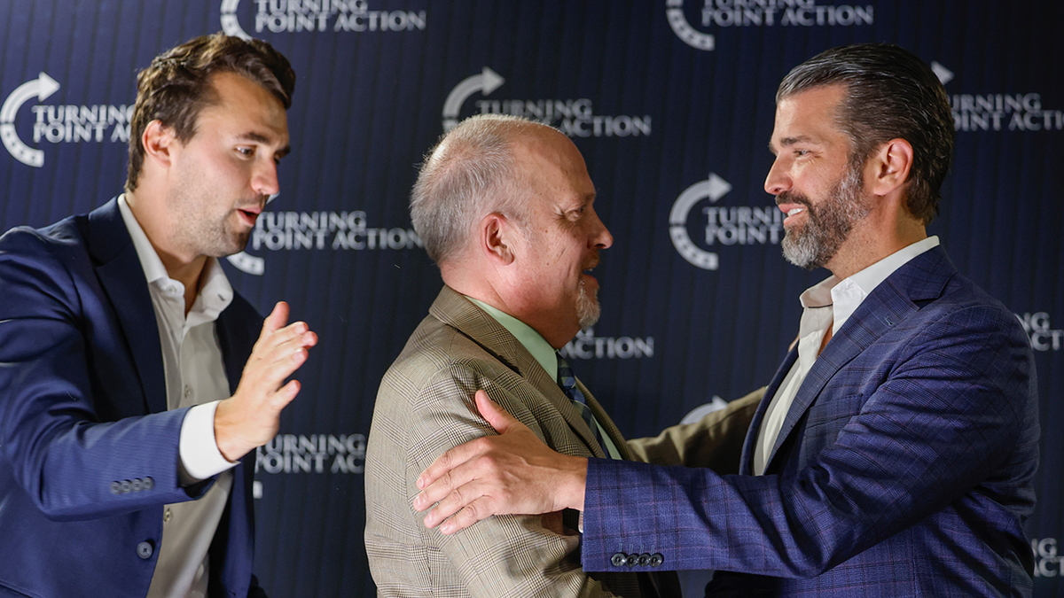 Former Wisconsin Attorney General and state Supreme Court candidate Brad Schimel, middle, greets Donald Trump Jr., as Charlie Kirk looks on during a town hall Monday, March 17, 2025, in Oconomowoc, Wis. (AP Photo/Jeffrey Phelps)