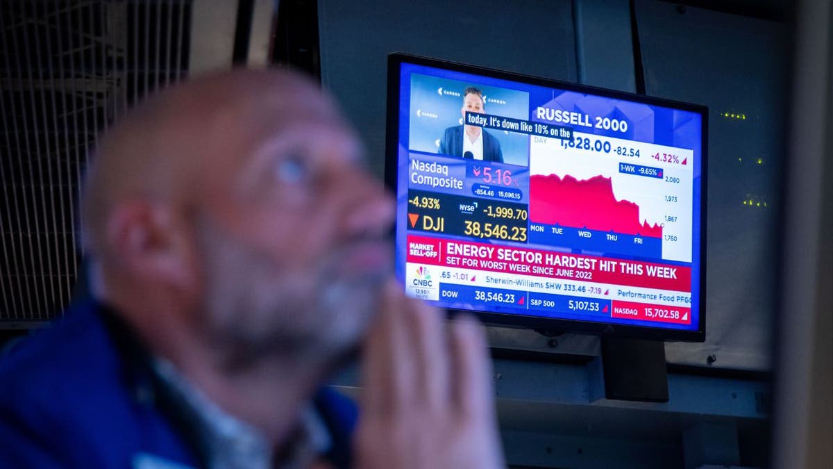 A man watches television screens showing news reports about the stock market
