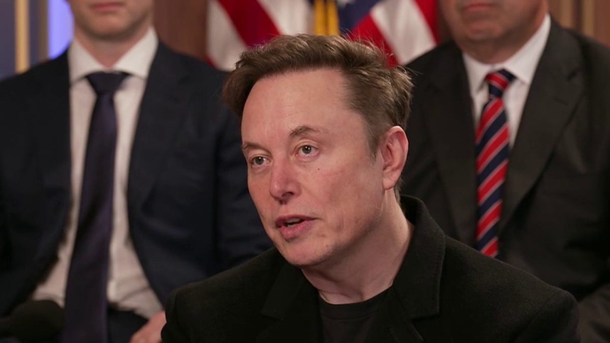 Elon Musk sits in front of other DOGE members in suits and ties