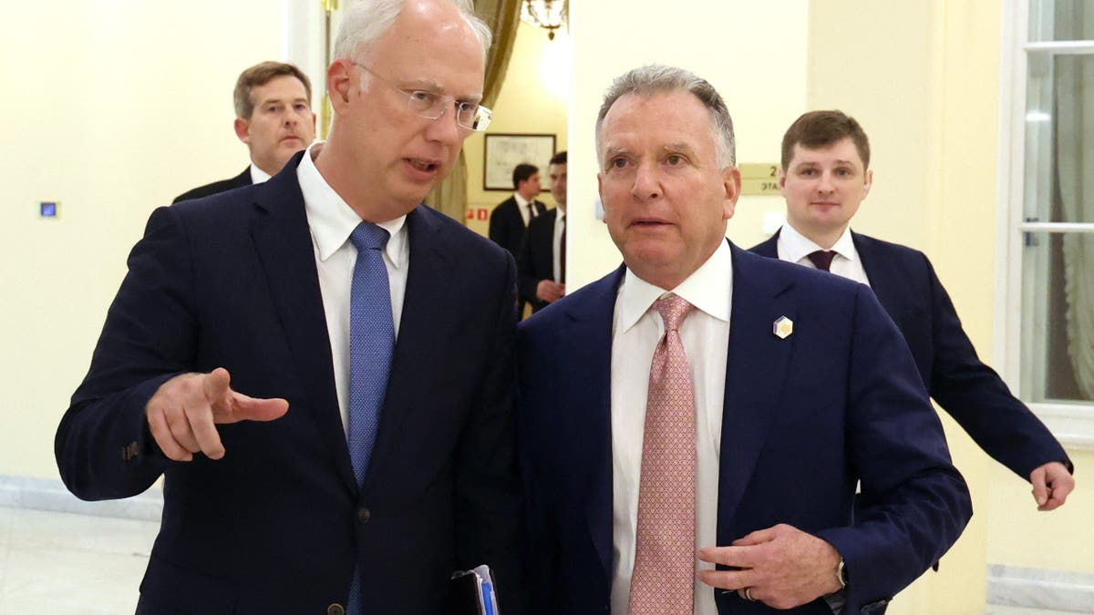 Kirill Dmitriev, CEO of the Russian Direct Investment Fund, speaks with Trump envoy Steve Witkoff during a meeting in a formal government building in Moscow. Both men wear suits and appear engaged in conversation, with other officials in the background.
