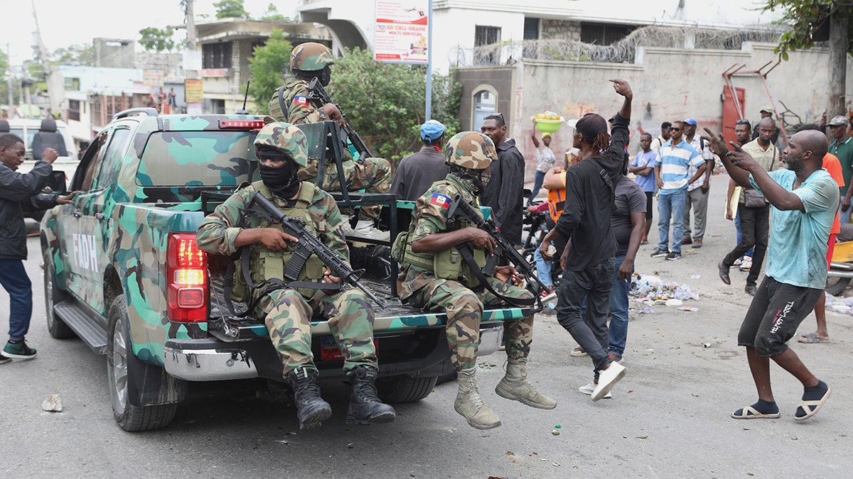 Armed men in camo in the back of a truck on a Haitian street