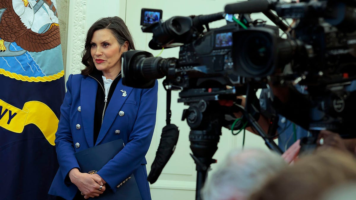 Whitmer stands next to news cameras in the Oval Office