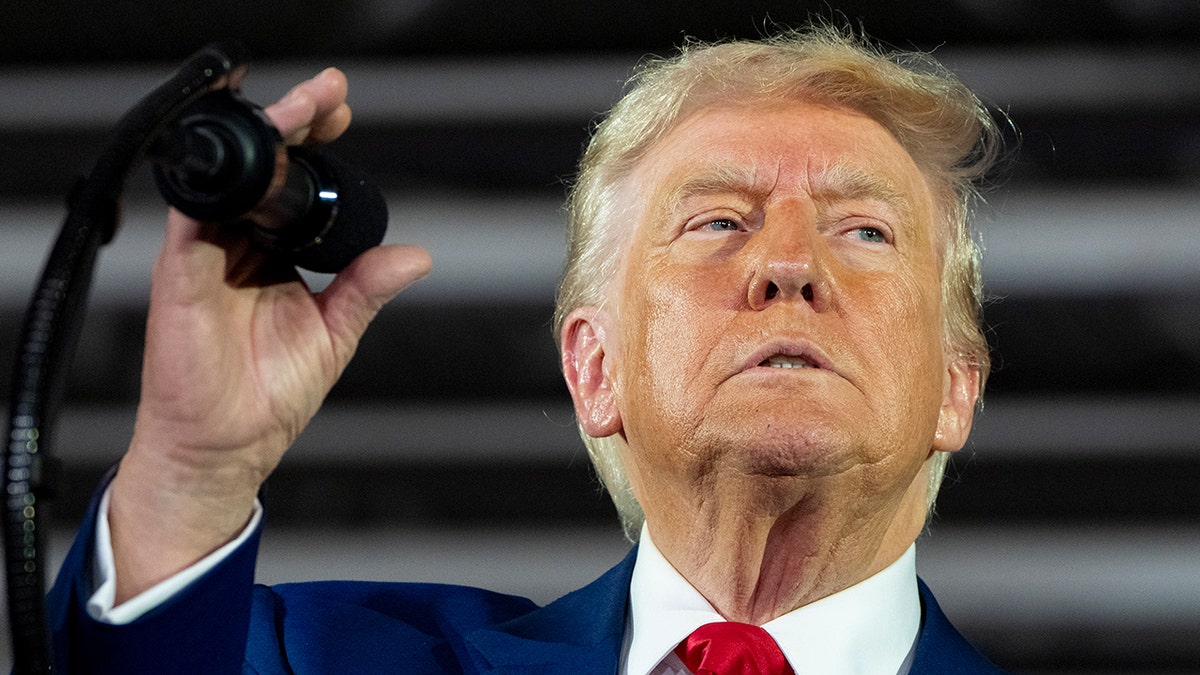 Trump holds microphone at Michigan 100 days rally 