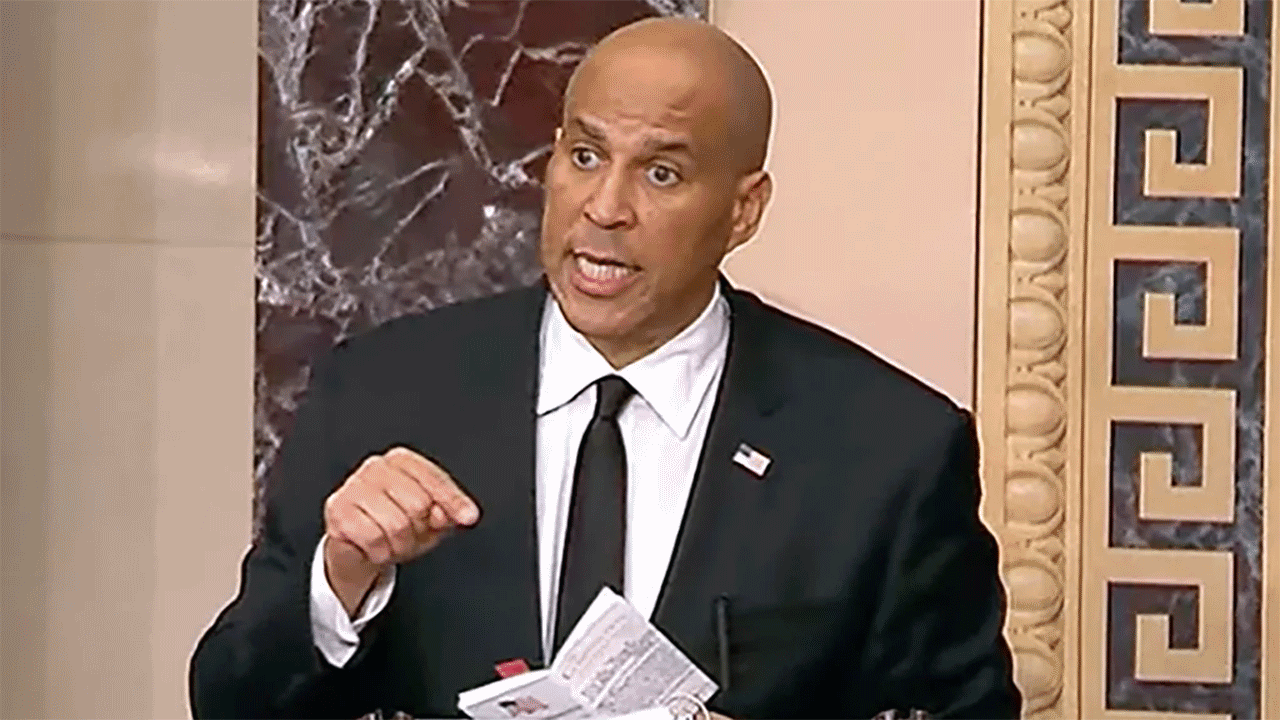 Cory Booker pointing at book in his hand