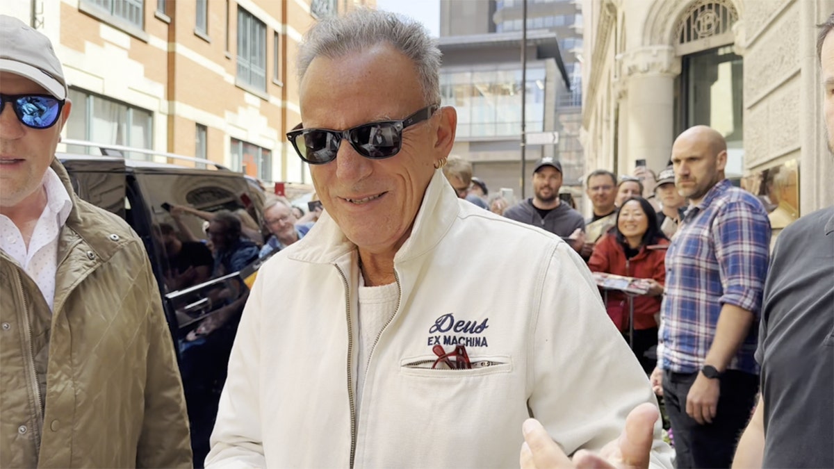 Bruce Springsteen signing autographs in a white coat