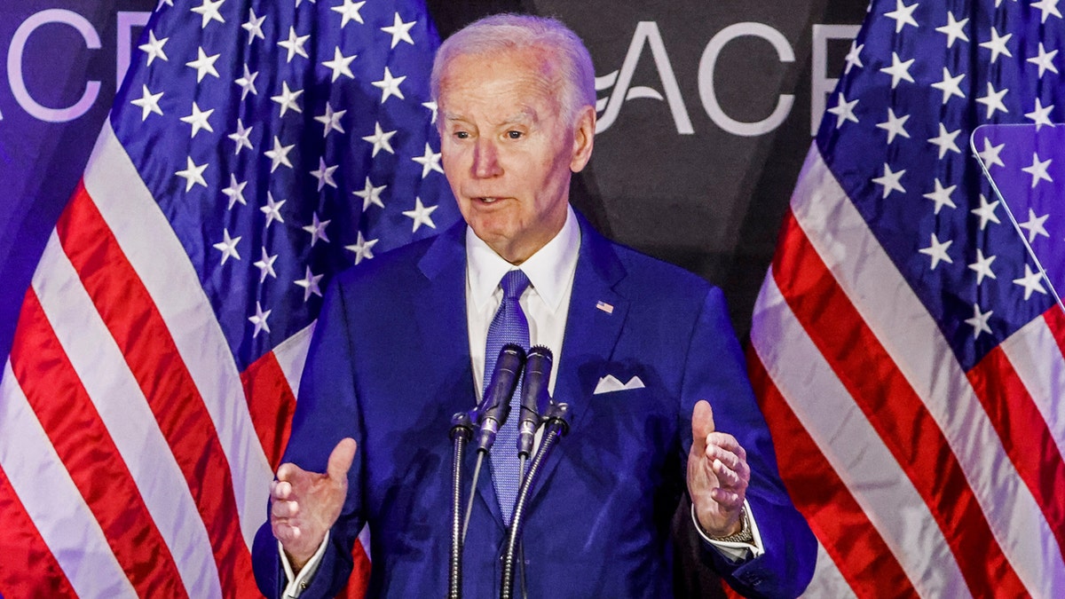 Joe Biden speaking with American flags in the background