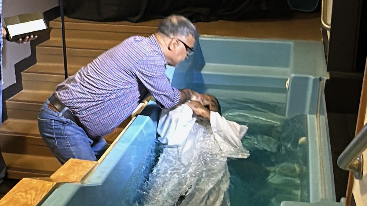 Pastor Basir baptizes a man in a small indoor pool during a church service at Oklahoma Khorasan Church, which serves Afghan Christian refugees