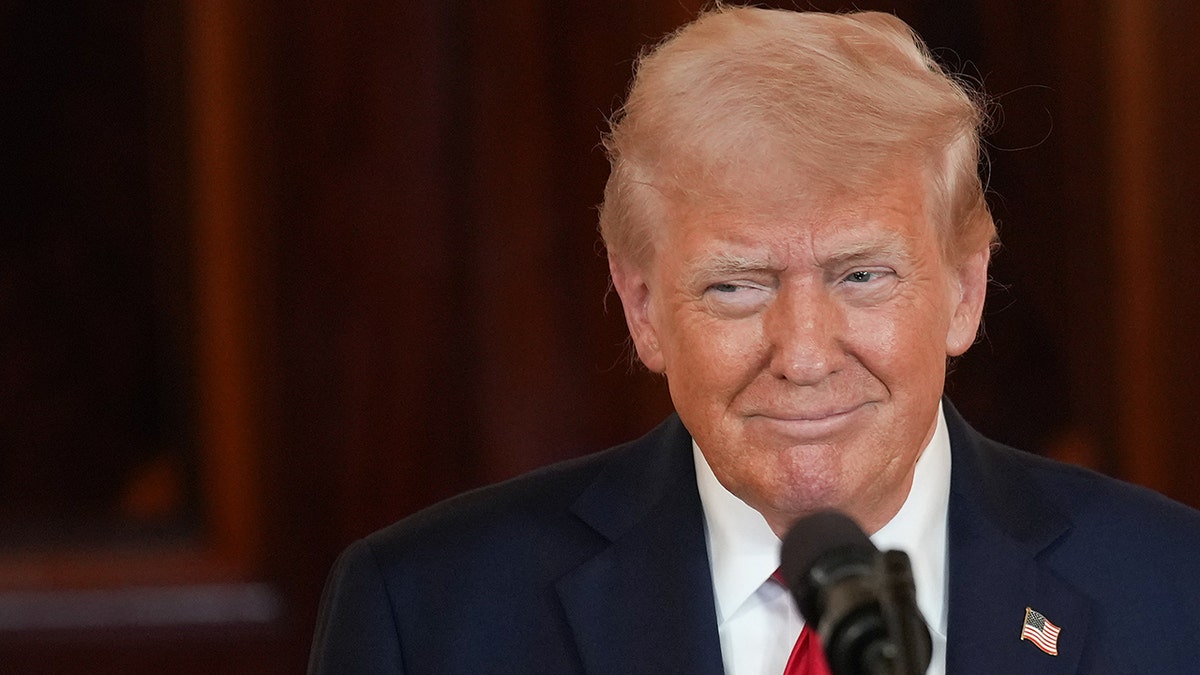 Trump in a red tie and navy suit speaks at the White House