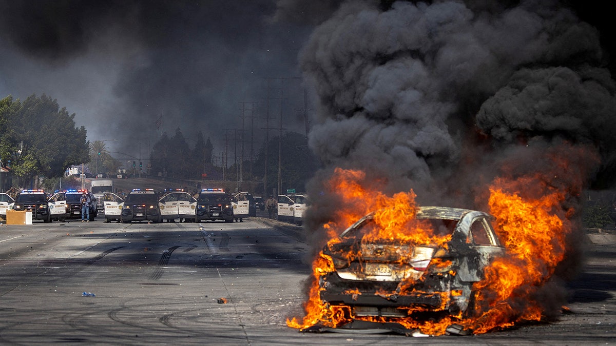 A car on fire in LA with multiple police cars in the background