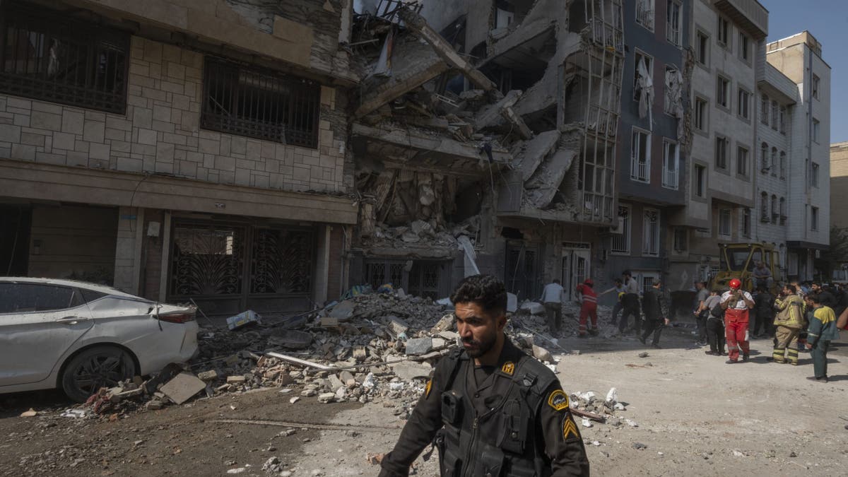 Iranian man on street, rubble behind him