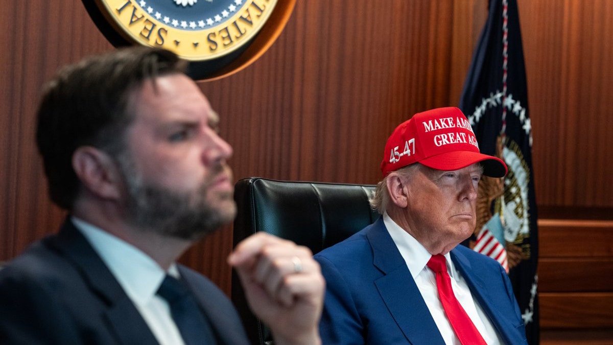President Donald Trump wearing a MAGA hat and J.D Vance look on in The Situation Room