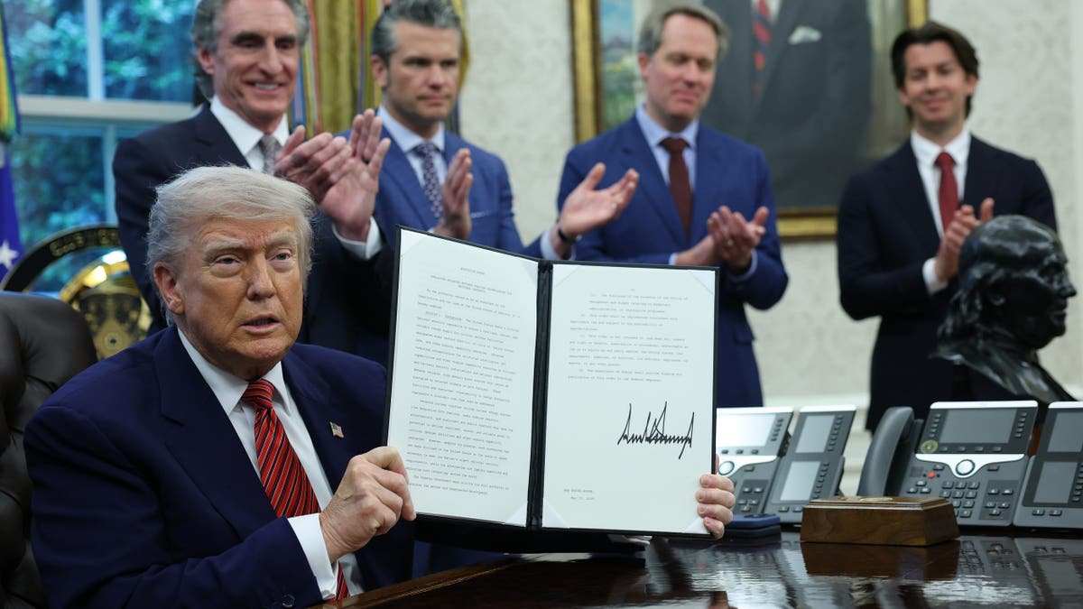 President Donald Trump holds up a signed executive order in the Oval Office of the White House on May 23, 2025 in Washington, D.C.