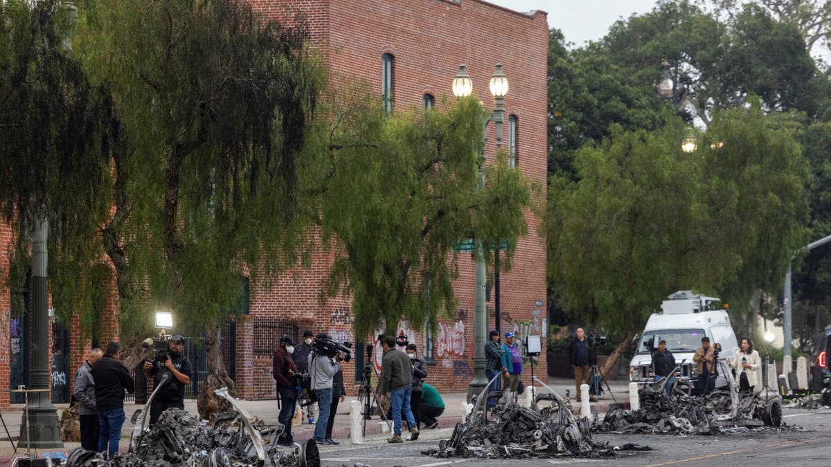 Members of the media report from Los Angeles Street where Waymo cars were burned yesterday, after the California National Guard was deployed by U.S. President Donald Trump as a response to protests against federal immigration sweeps, in downtown Los Angeles, California, U.S., June 9, 2025