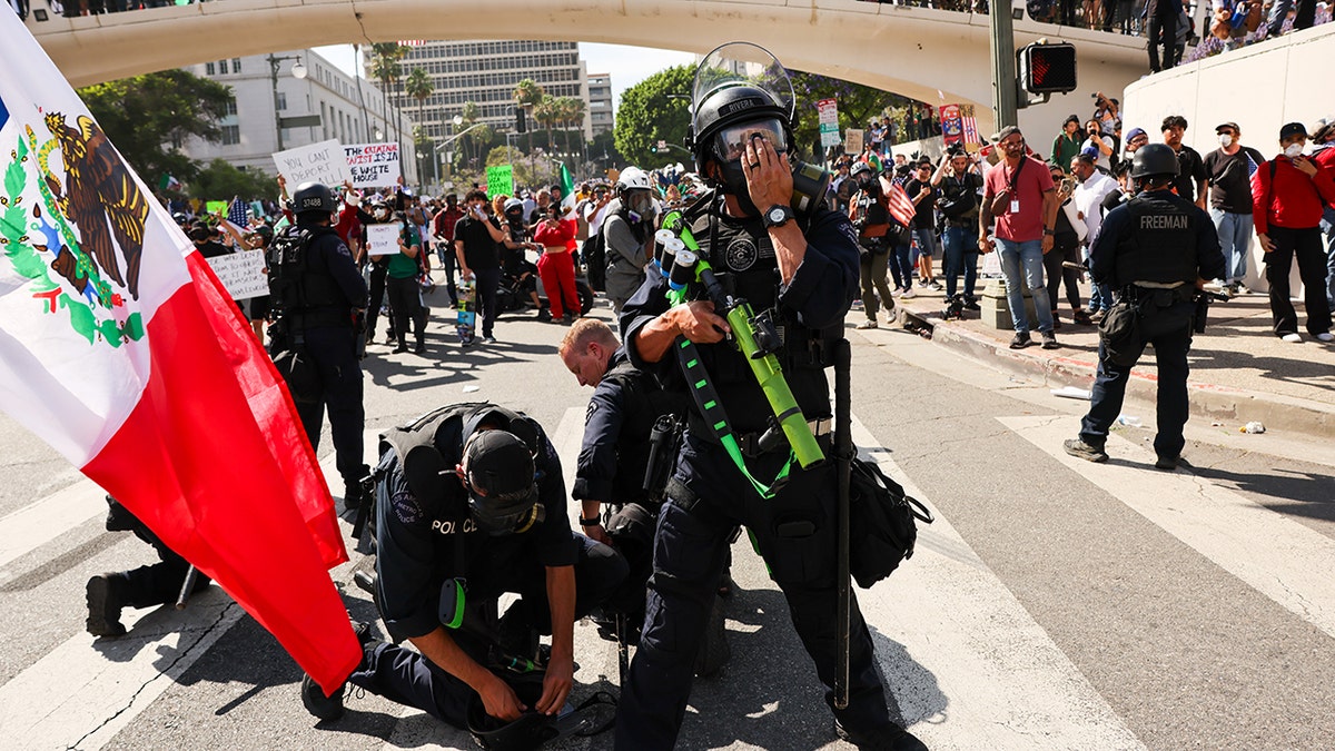 police detaining rioter, Mexican flag to left of photo