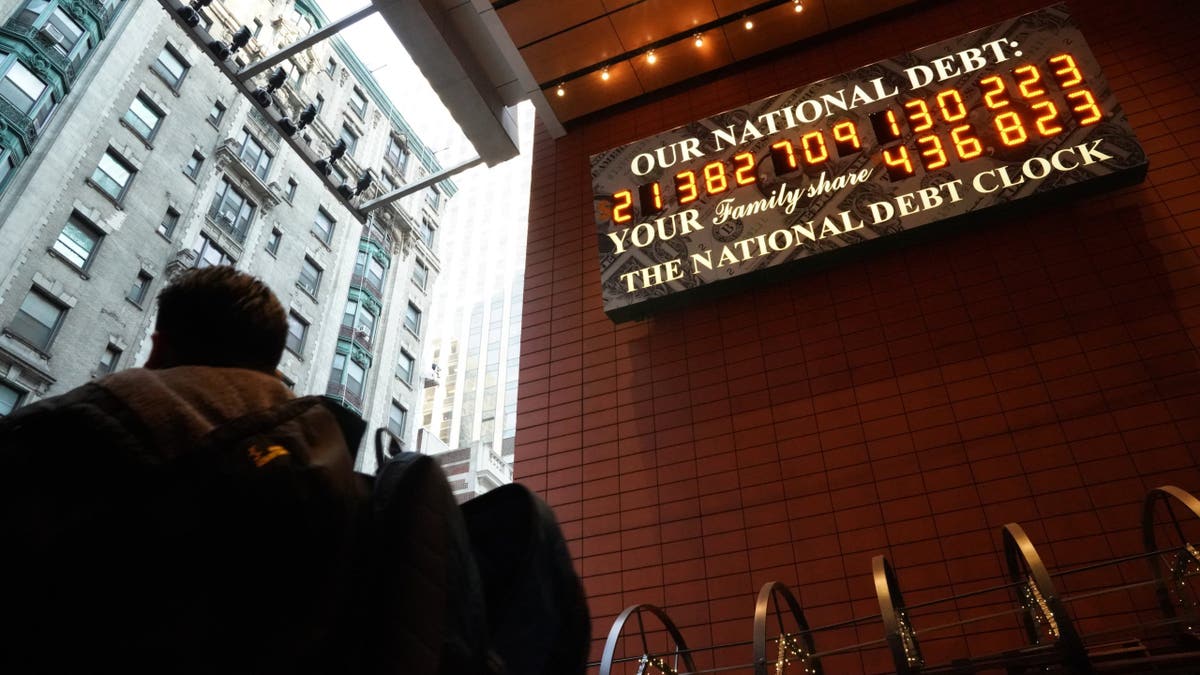 A man walks past the National Debt Clock on 43rd Street in New York City. The billboard constantly updates to display the current U.S. gross national debt and each American family's share of the debt.