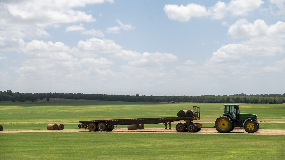 A tractor collects bales of hay during a heatwave outside Elgin, Texas, on Wednesday, July 20, 2022. 