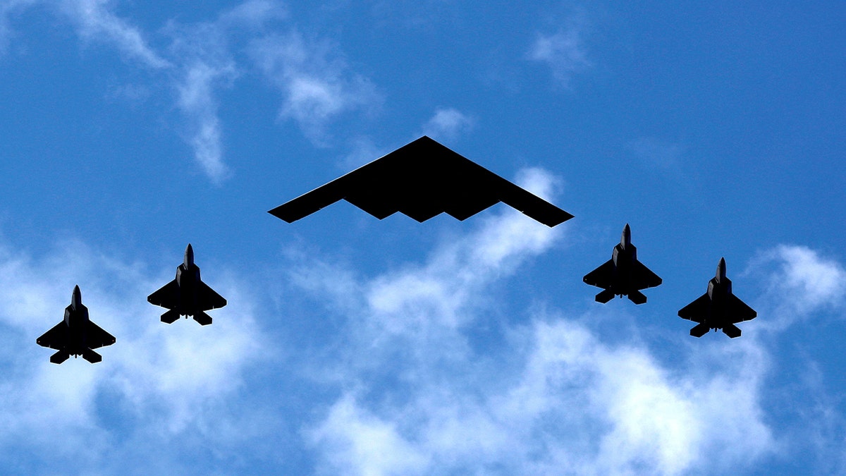 U.S. Air Force B-2 Spirit Stealth Bomber flanked by 4 U.S. Marine Corps F-35 fighters