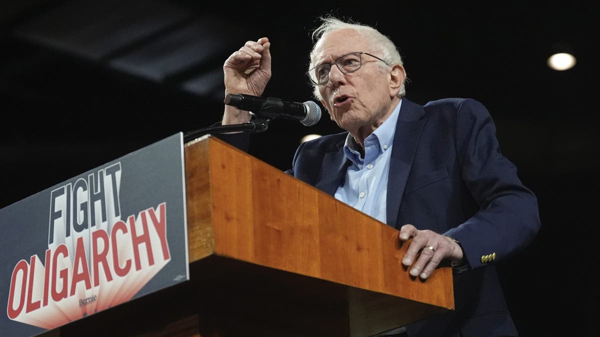 Bernie Sanders speaks at a podium with a sign that reads, "Fight Oligarchy"