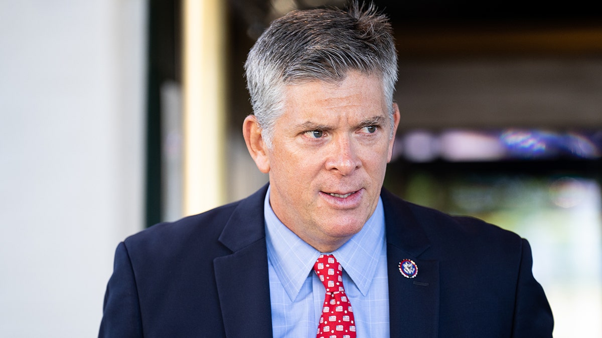 LaHood leaving Republican Conference meeting in a blue suit and red tie