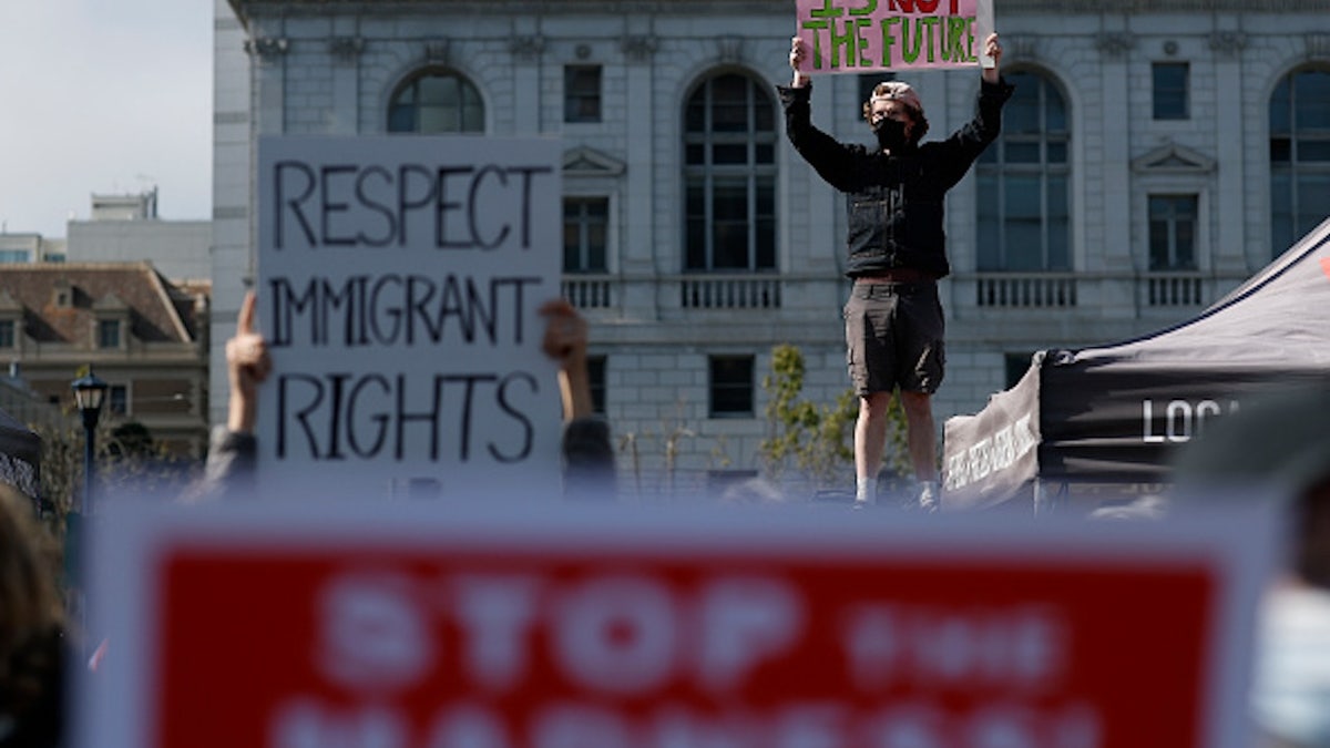 Protesters hold signs during a May Day demonstration and march at San Francisco City Hall.