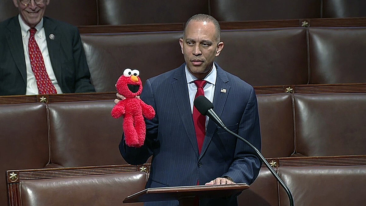 Rep. Hakeem Jeffries holds an Elmo doll while speaking at the House podium during debate on the GOP budget bill.