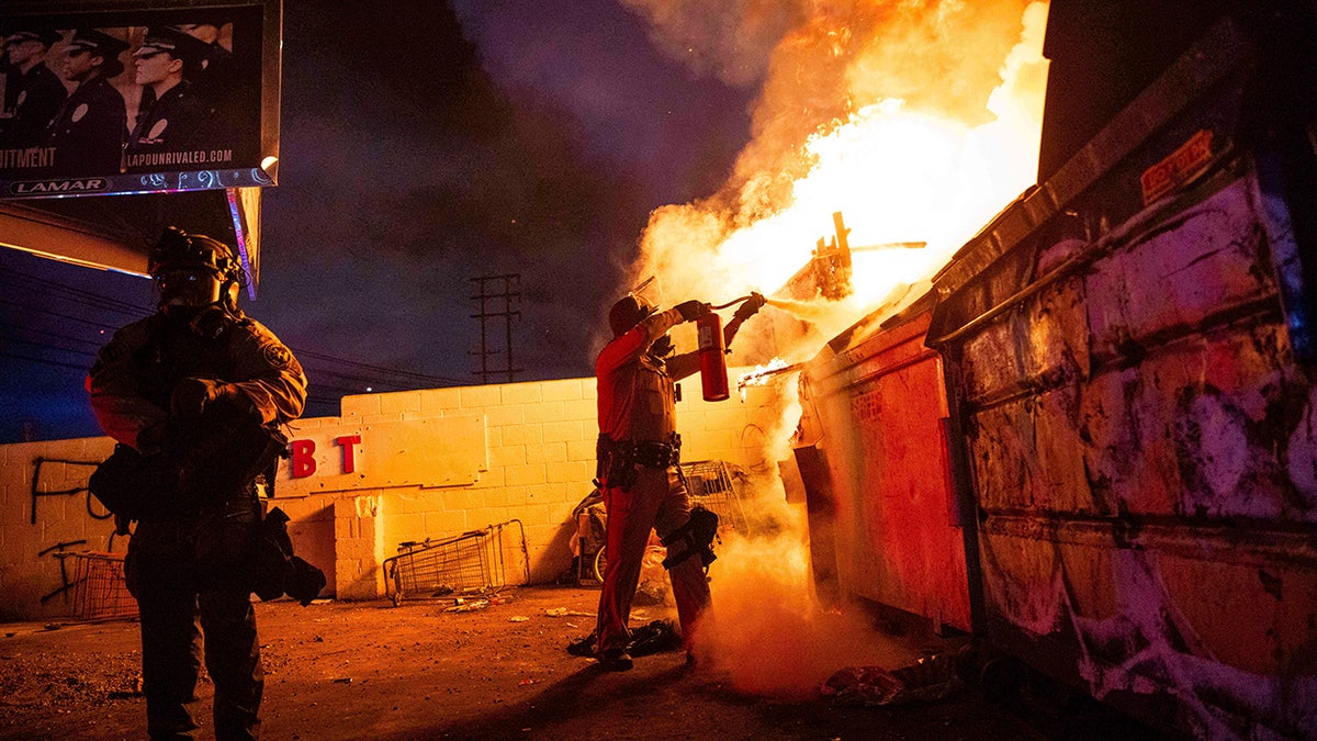 A law enforcement officer works to put out a fire during a protest in Compton, Calif., Saturday, June 7, 2025, after federal immigration authorities conducted operations.