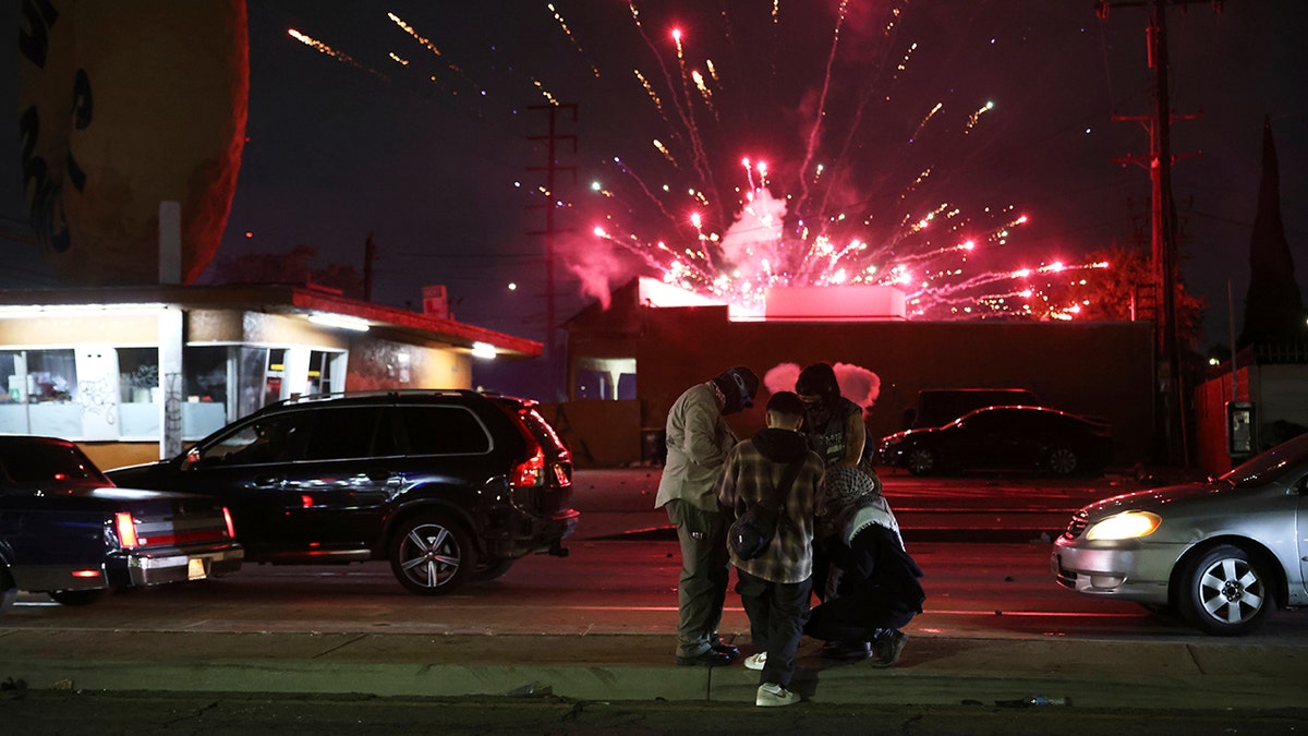protesters at night in LA , fireworks in background