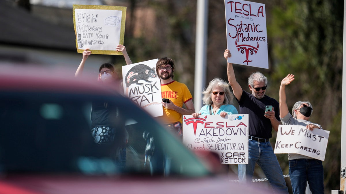 People protest automaker billionaire CEO Elon Musk near a Tesla vehicle dealership, March 8, 2025, in Decatur, Ga.