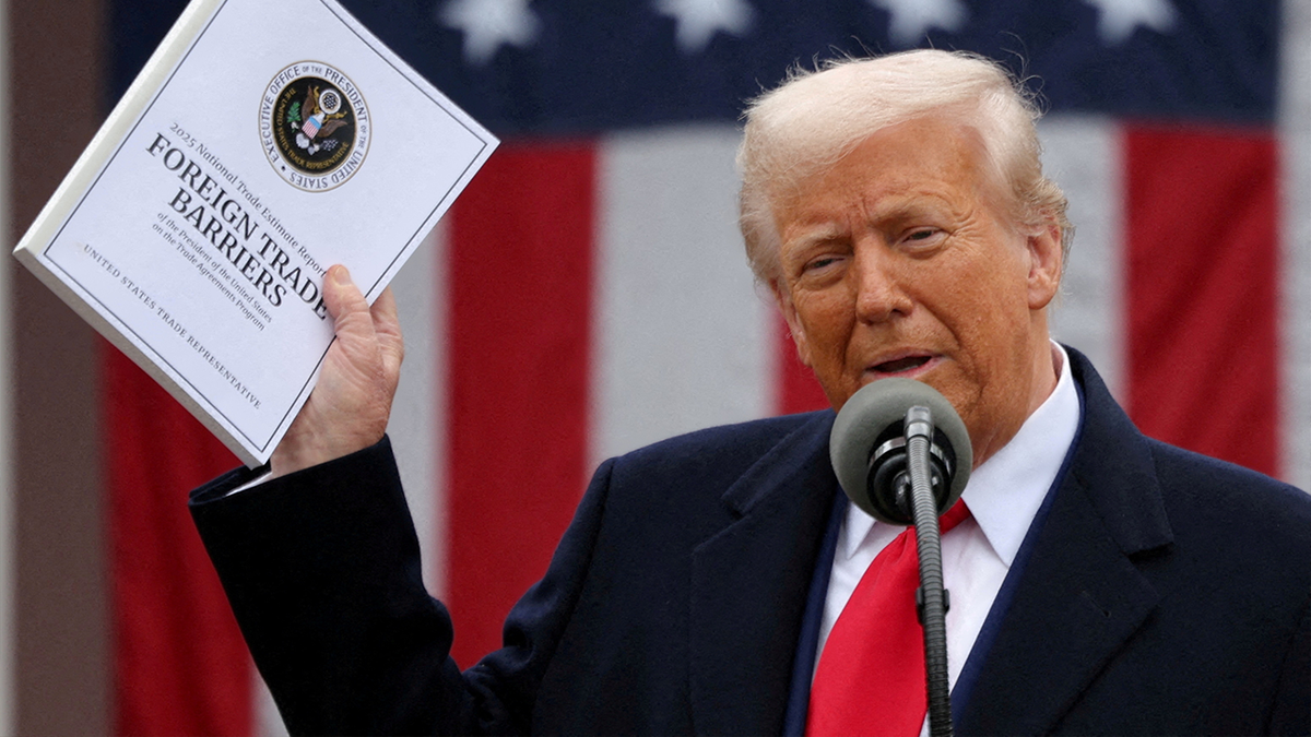 Donald Trump holds up document titled, "Foreign Trade Barriers"