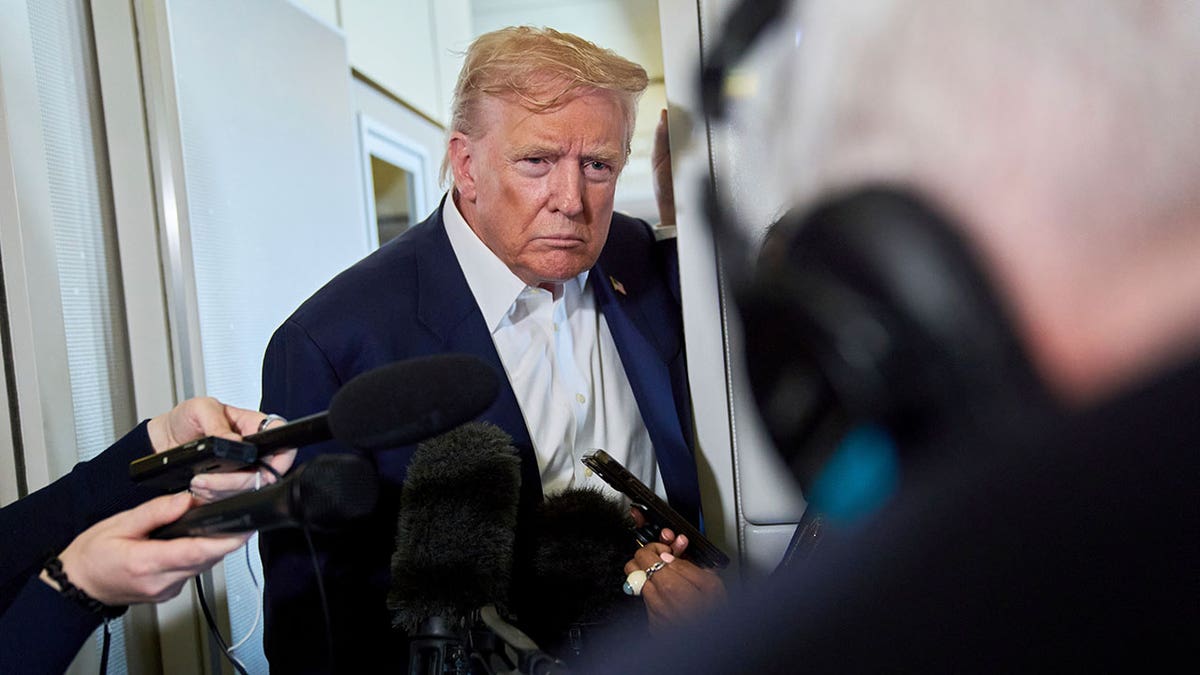 President Donald Trump leaning in while fielding questions from reporters aboard Air Force One