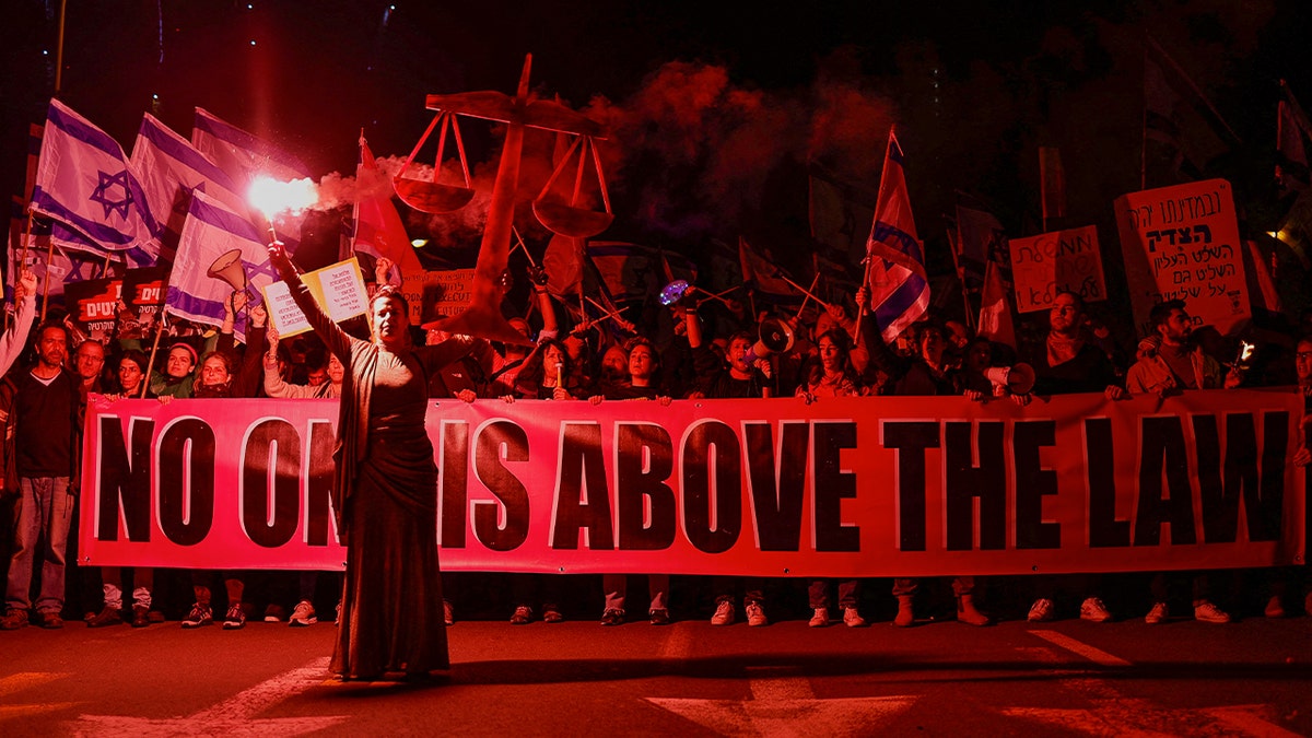 Israelis hold a banner reading "no one is above the law" during an anti-Netanyahu protest