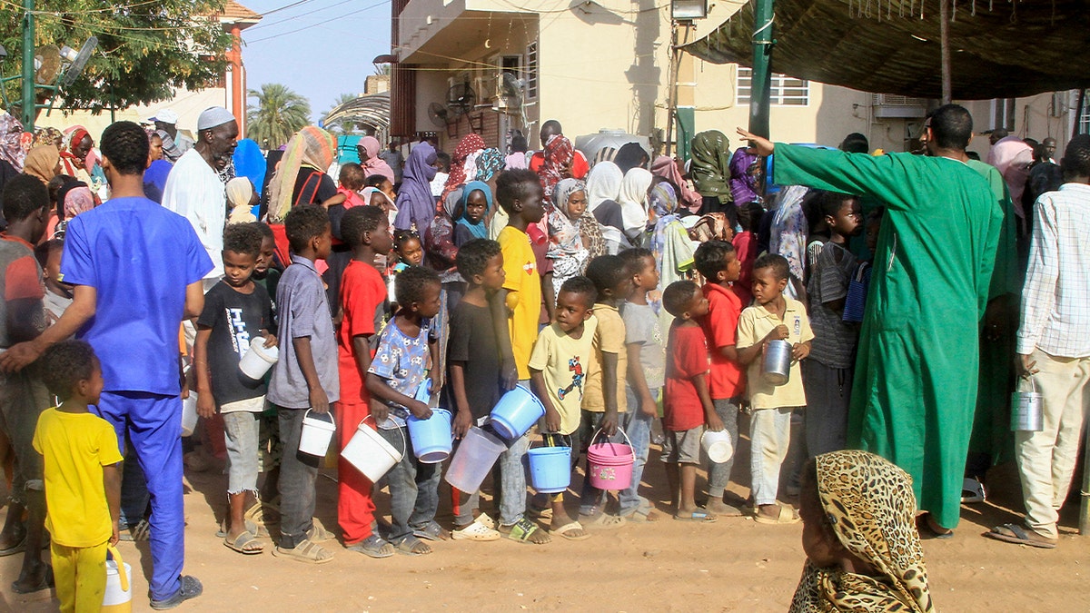 Sudanese line up to collect a charity "iftar" fast breaking meal in Omdourman, on March 19, 2025