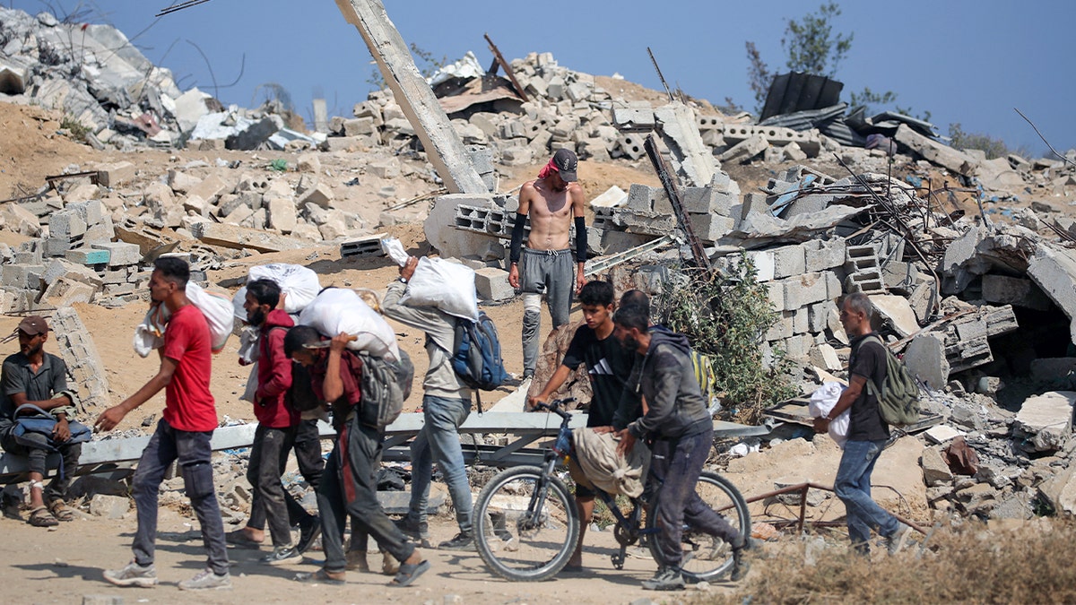 Palestinians return with bags from a food distribution point run by the US and Israeli-backed Gaza Humanitarian Foundation (GHF) group, near the Netsarim corridor in the central Gaza Strip on Aug. 2, 2025.