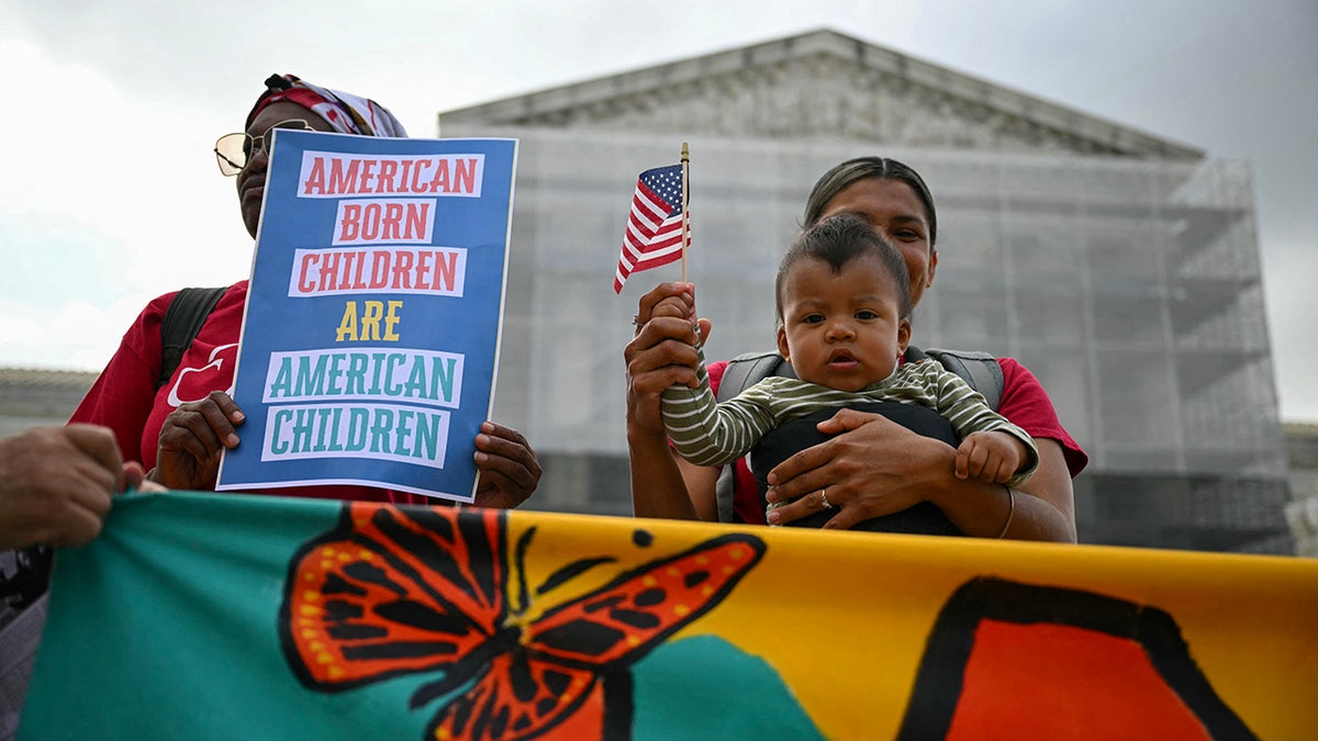 Woman holds sign protesting President Donald Trump's birthright citizenship order