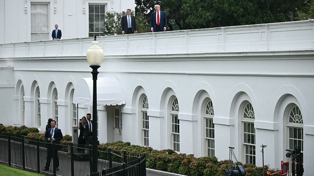 US President Donald Trump surveys the grounds of the White House from the roof, in Washington, DC, on August 5, 2025.