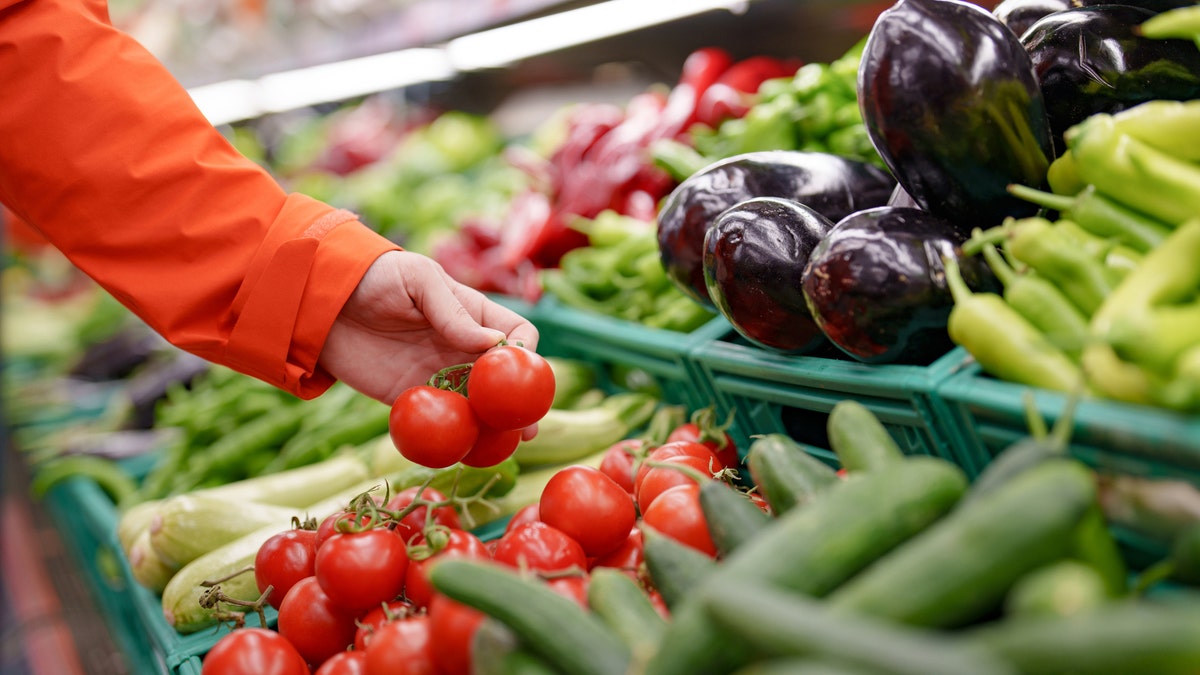 hand holding tomatoes in produce section