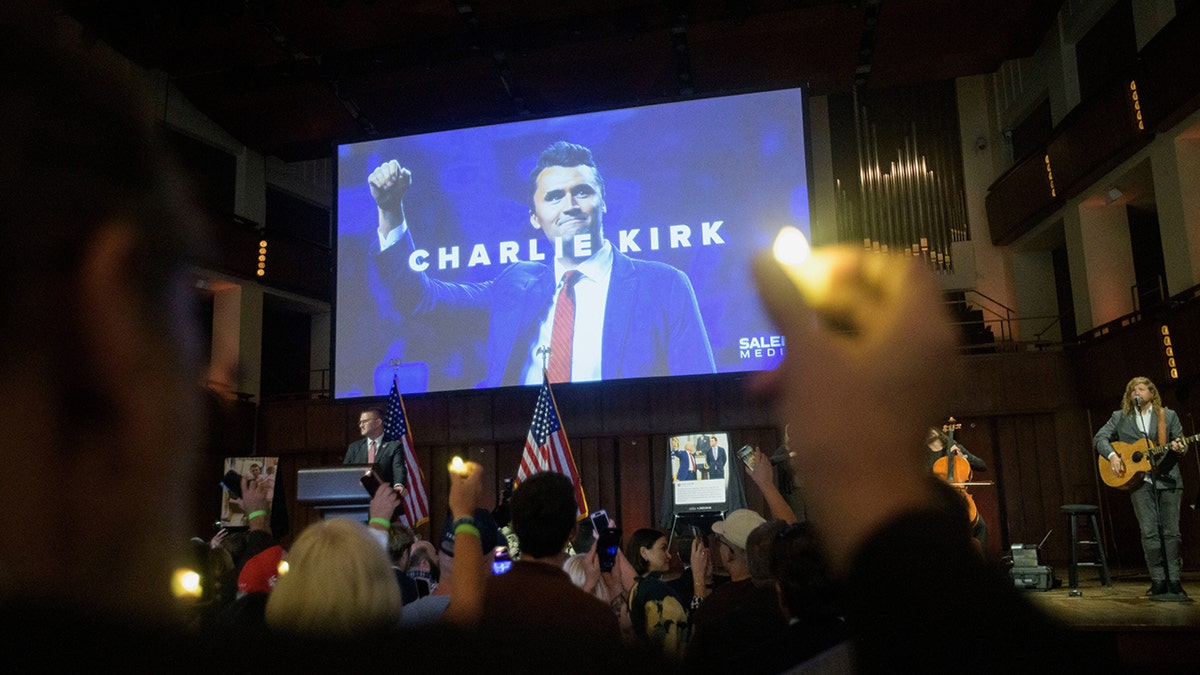 People hold candles and sing during a memorial for Charlie Kirk