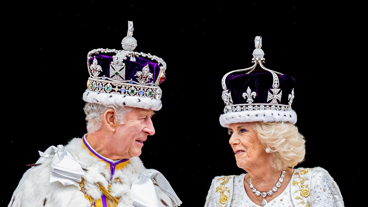 Queen Camilla and King Charles admiring each other in crowns and royal robes.