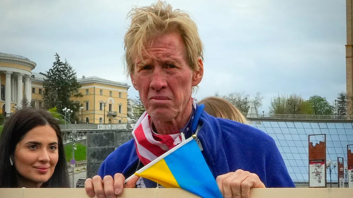 Ryan Wesley Routh looking serious while holding Ukrainian flag