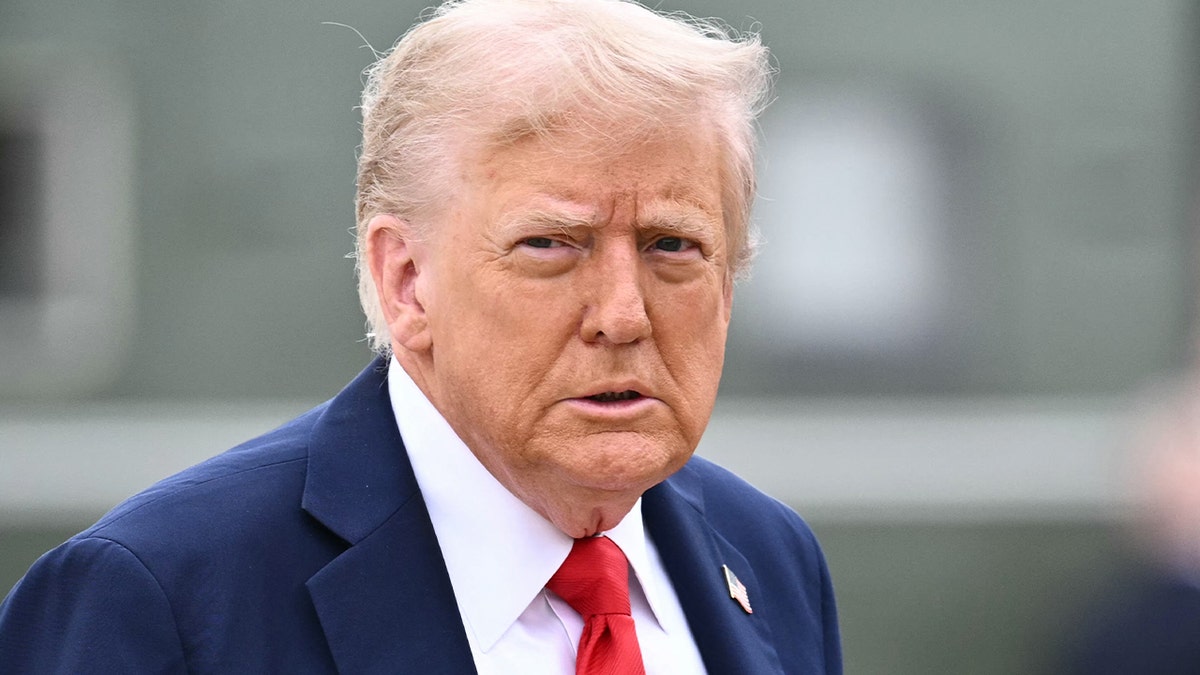 Donald trump wearing suit and tie looking stern