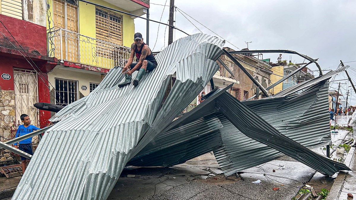 Person sits on roof of home damaged by Hurricane Melissa in Cuba