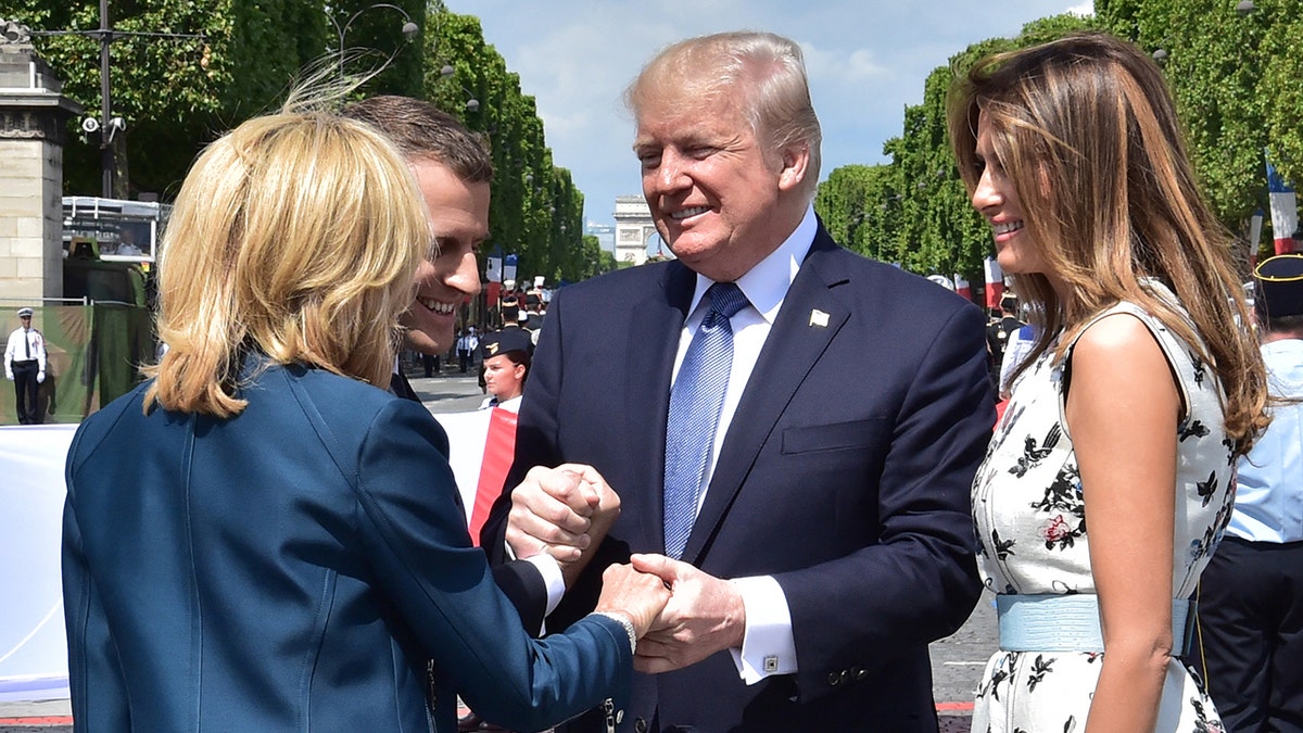 U.S. President Donald Trump, flanked by first lady Melania Trump, clasps the hand of French President Emmanuel Macron and the hand of Macron's wife Brigitte Macron