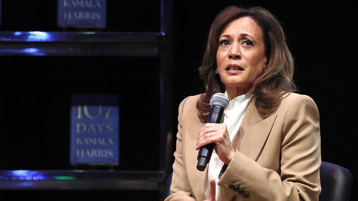 Kamala Harris addresses a crowd on stage with a microphone at the Wiltern Theatre.