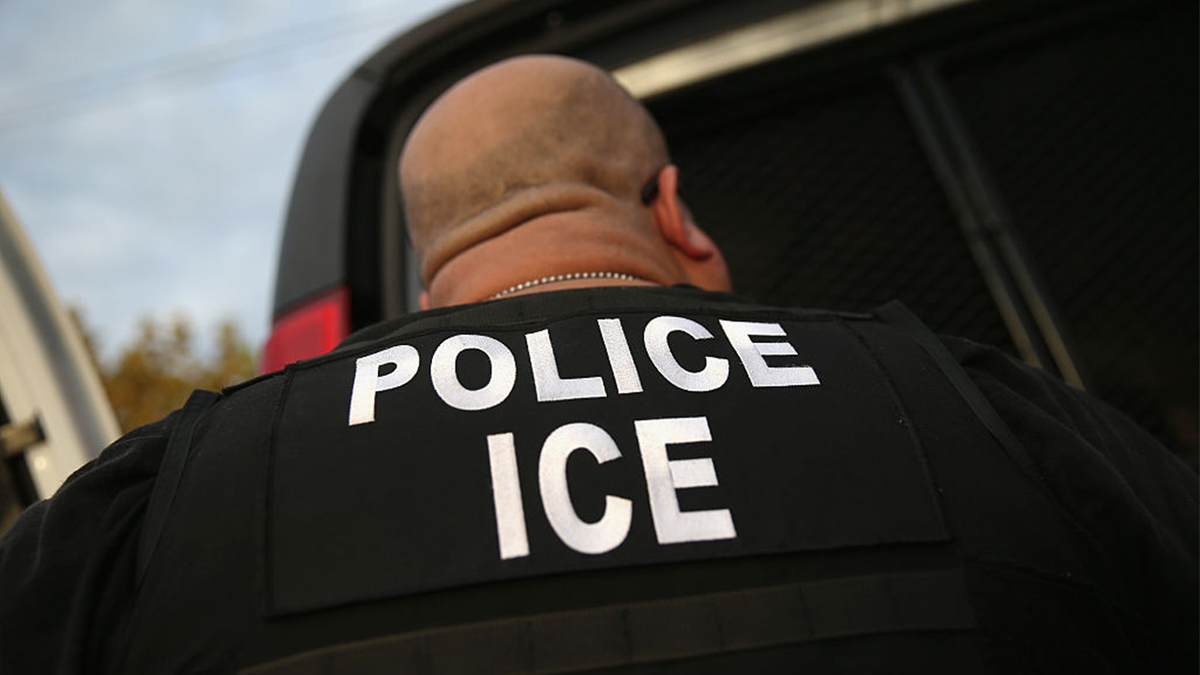 ICE agent with his back turned to the camera.