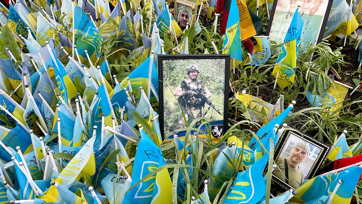 Blue and yellow Ukrainian flags and framed photos honor fallen soldiers at a military memorial site in Kyiv, Ukraine, in April 2024.