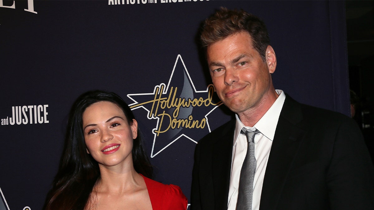 Vince Offer in suit next to wife in red dress.
