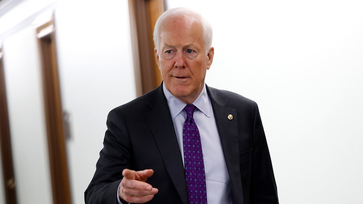 Sen. John Cornyn points in a hallway