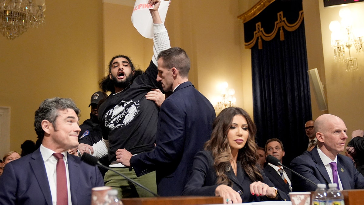 A protester stands and shouts during a congressional hearing with senior U.S. national security officials.