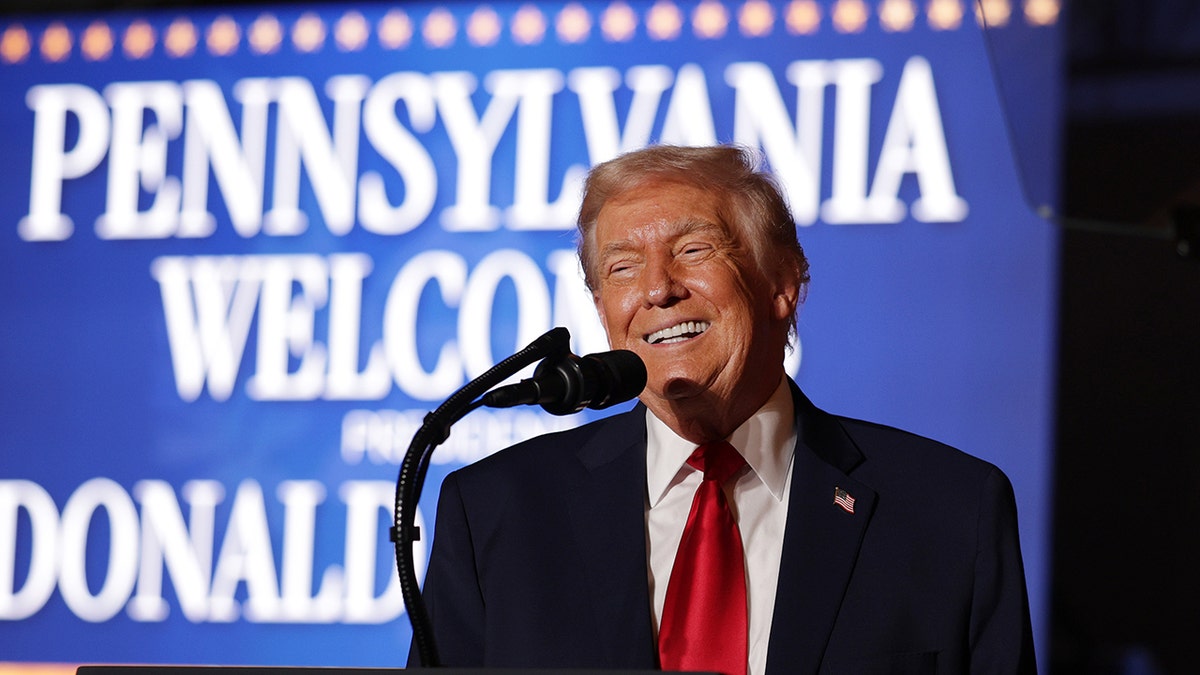 President Donald Trump smiles while speaking at podium