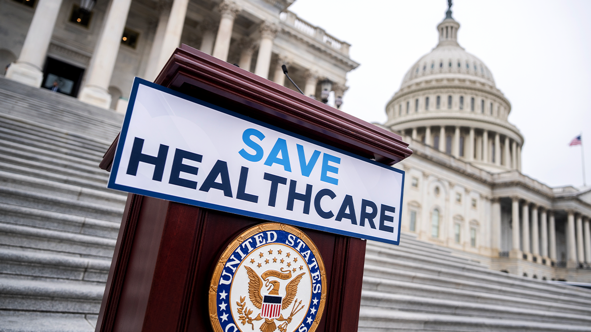 A "save healthcare" sign outside the Capitol